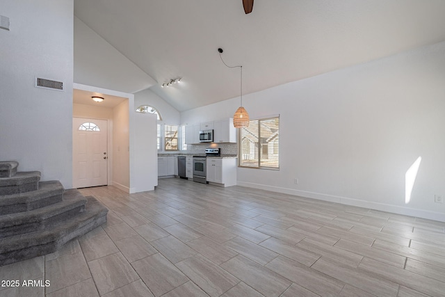 unfurnished living room featuring high vaulted ceiling and rail lighting