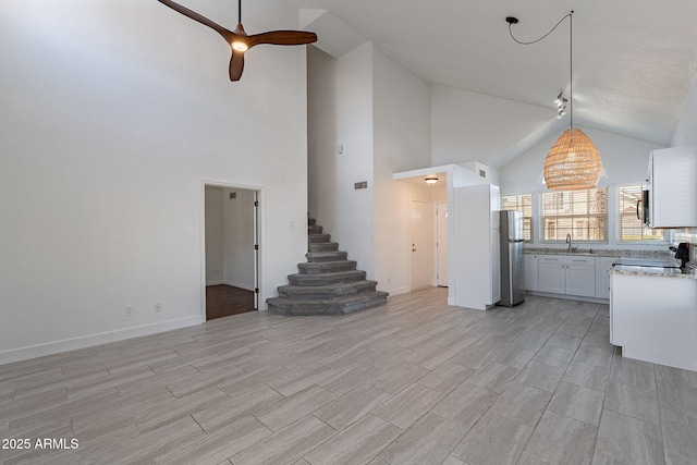 unfurnished living room featuring lofted ceiling, sink, and ceiling fan