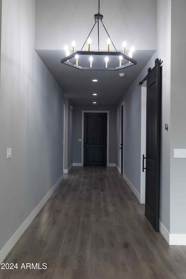 corridor with dark wood-type flooring and a barn door