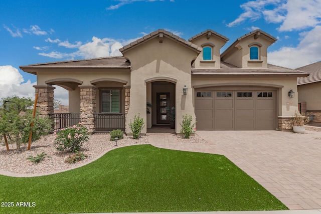 mediterranean / spanish home featuring stone siding, decorative driveway, stucco siding, a garage, and a front lawn