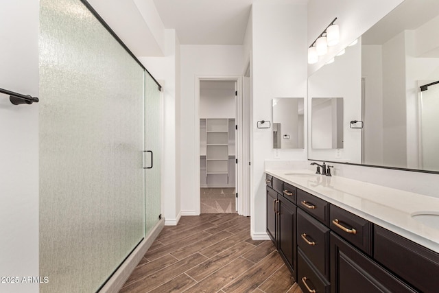full bath with wood finished floors, a shower stall, and double vanity