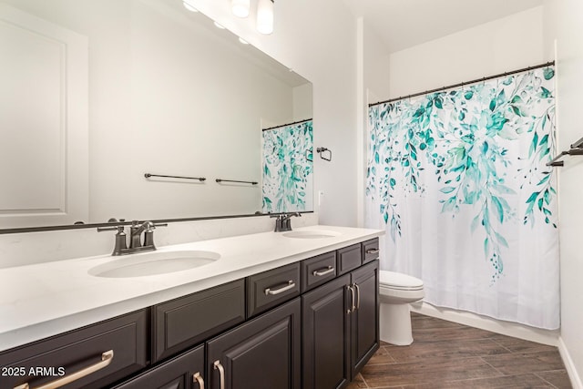 bathroom featuring double vanity, toilet, and wood finished floors