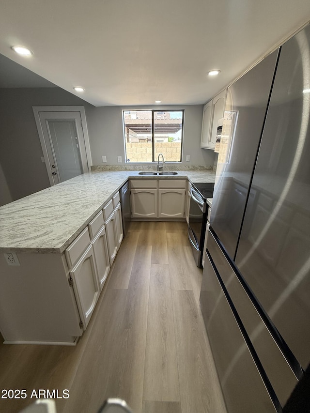 170 E Guadalupe Rd Unit 173, Gilbert, AZ 85234 - kitchen with appliances with stainless steel finishes, a sink, light wood-style flooring, a peninsula, and light stone countertops