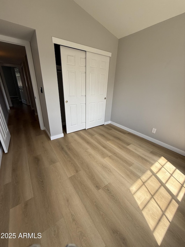 170 E Guadalupe Rd Unit 173, Gilbert, AZ 85234 - unfurnished bedroom with lofted ceiling, wood finished floors, baseboards, and a closet
