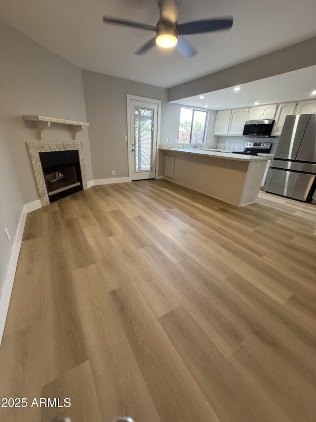 170 E Guadalupe Rd Unit 173, Gilbert, AZ 85234 - unfurnished living room with light wood-type flooring, a ceiling fan, a fireplace, and baseboards