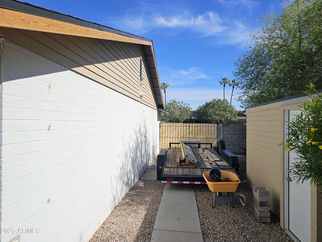view of property exterior featuring fence, an outbuilding, a storage unit, and a deck
