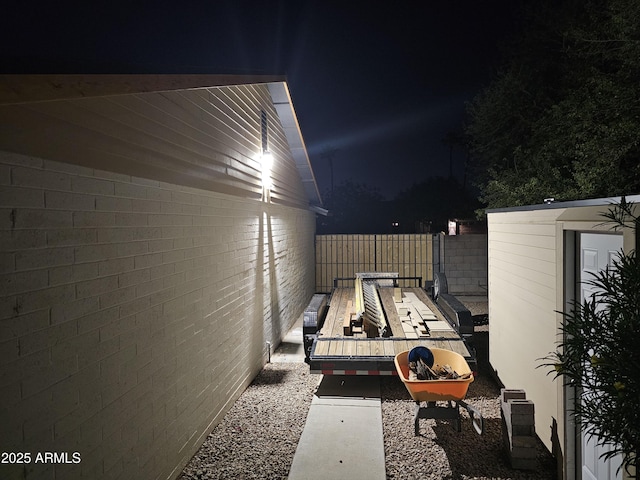 patio at twilight with fence and an outdoor structure