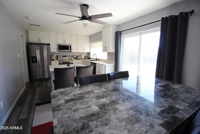 kitchen featuring dark wood-type flooring, sink, a center island, stainless steel appliances, and white cabinets