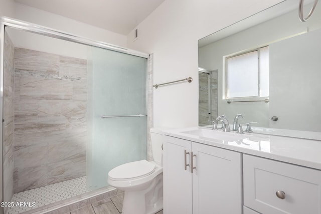 bathroom with vanity, toilet, and a shower with door