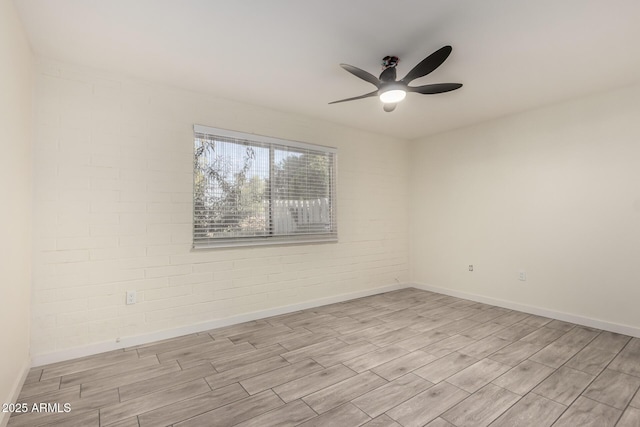 unfurnished room featuring ceiling fan and brick wall