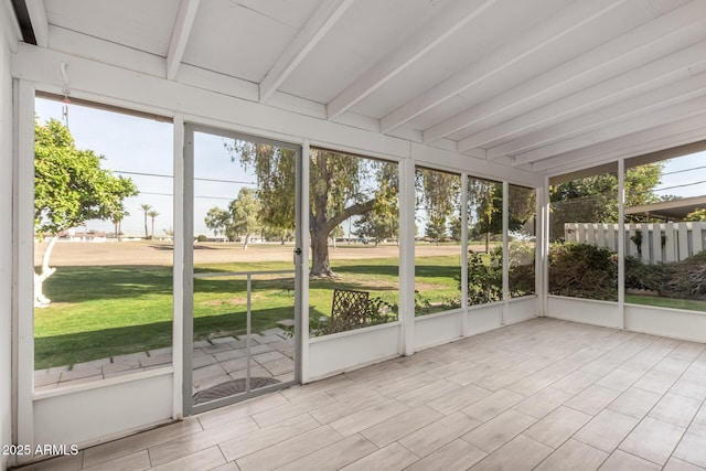 unfurnished sunroom featuring vaulted ceiling with beams