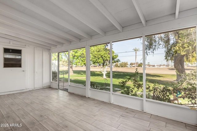 unfurnished sunroom featuring vaulted ceiling with beams