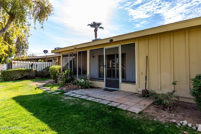 back of property featuring a patio, a yard, and a sunroom