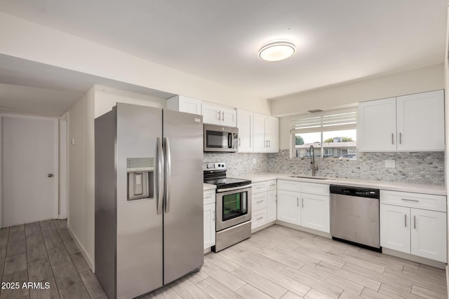 kitchen featuring appliances with stainless steel finishes, decorative backsplash, sink, and white cabinets