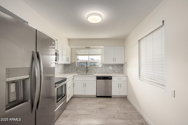 kitchen with appliances with stainless steel finishes, decorative backsplash, sink, and white cabinets