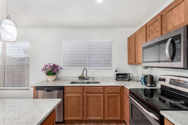 kitchen with stainless steel appliances, hanging light fixtures, sink, and light stone counters