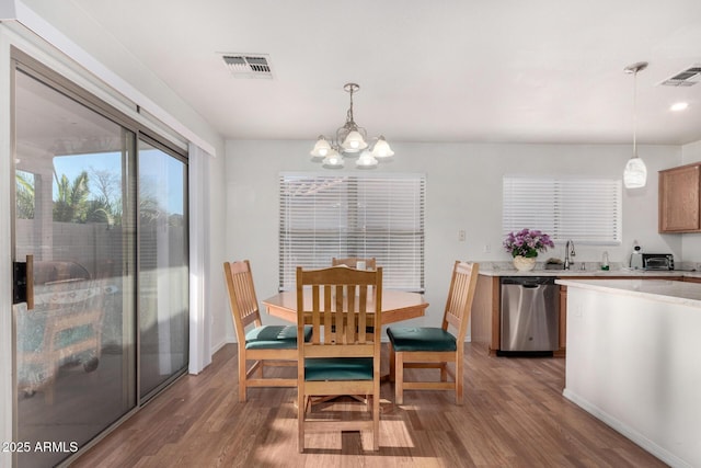 dining space with hardwood / wood-style flooring, sink, and a notable chandelier