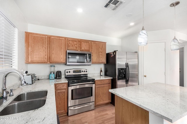 kitchen featuring sink, hanging light fixtures, light hardwood / wood-style floors, stainless steel appliances, and light stone countertops