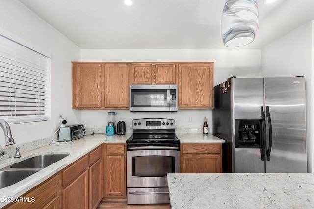 kitchen with sink, stainless steel appliances, and light stone countertops