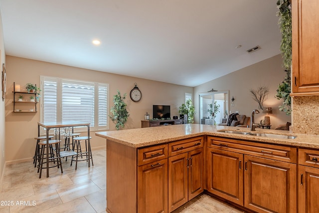 490 W Encinas St, Gilbert, AZ 85233 - kitchen featuring a sink, light stone counters, brown cabinetry, a peninsula, and lofted ceiling
