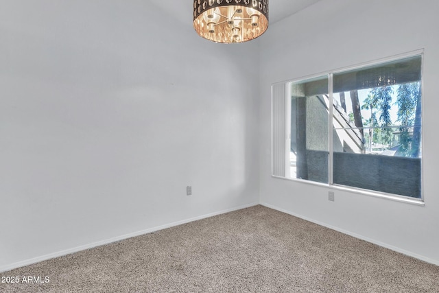 carpeted spare room with a notable chandelier