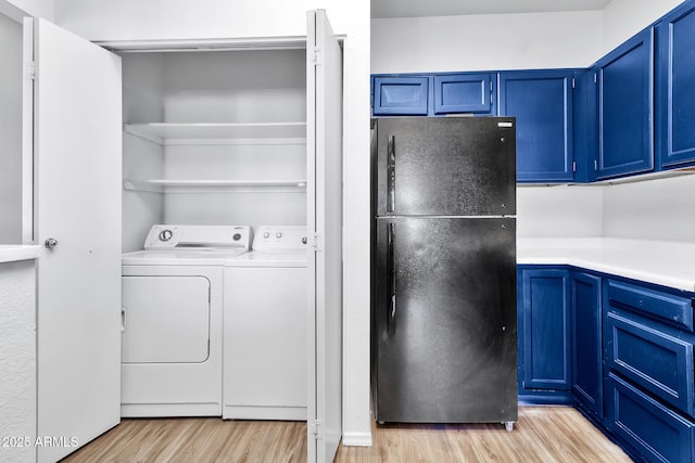 clothes washing area with washer and dryer and light hardwood / wood-style floors