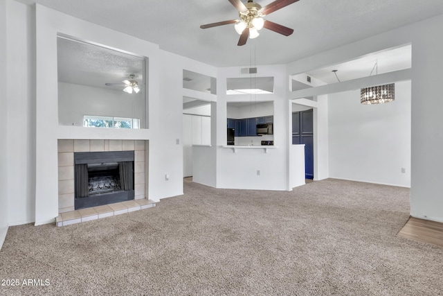 unfurnished living room featuring a fireplace, light carpet, a textured ceiling, and ceiling fan