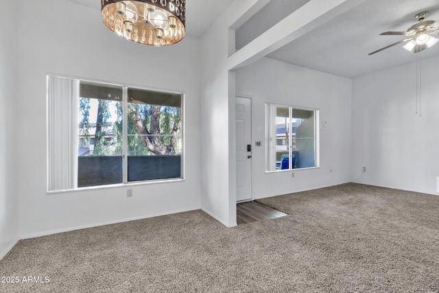 carpeted entrance foyer with ceiling fan with notable chandelier