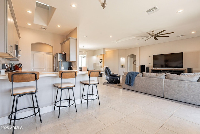 kitchen featuring arched walkways, a peninsula, open floor plan, appliances with stainless steel finishes, and a kitchen bar