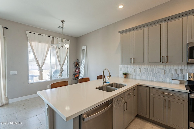 kitchen featuring appliances with stainless steel finishes, light countertops, a sink, and a peninsula