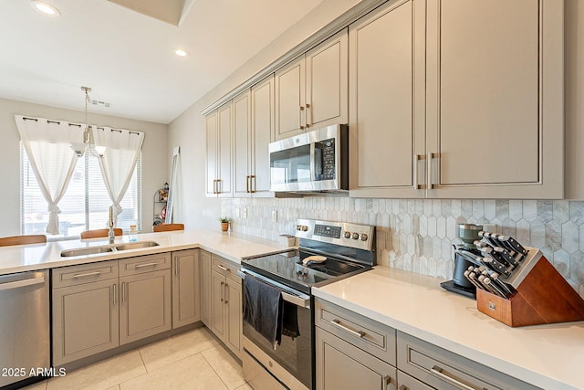 kitchen featuring light tile patterned flooring, a sink, light countertops, appliances with stainless steel finishes, and tasteful backsplash