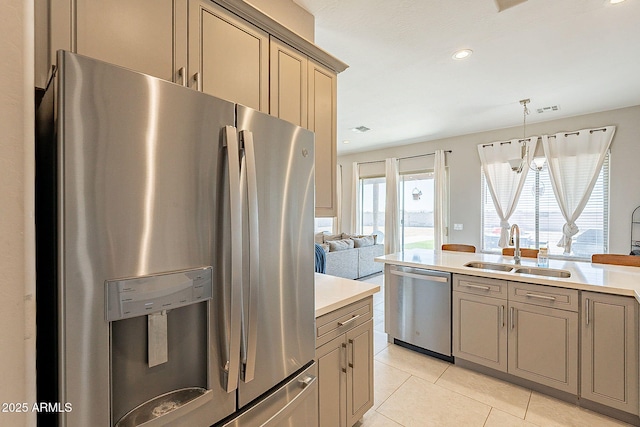 kitchen with light tile patterned flooring, stainless steel appliances, a sink, light countertops, and pendant lighting