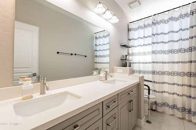 bathroom featuring double vanity, visible vents, a sink, and tile patterned floors