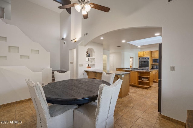 dining area featuring arched walkways, recessed lighting, a ceiling fan, light tile patterned flooring, and baseboards