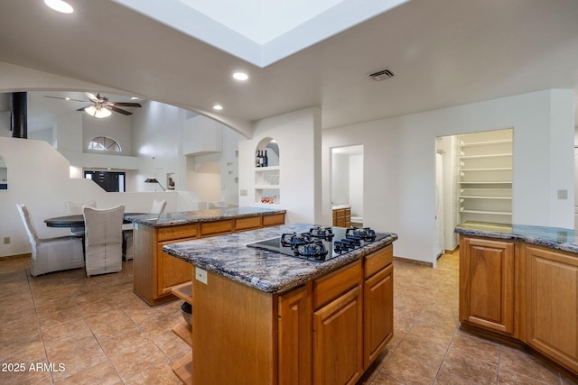 kitchen with black stovetop, visible vents, dark stone countertops, and a center island