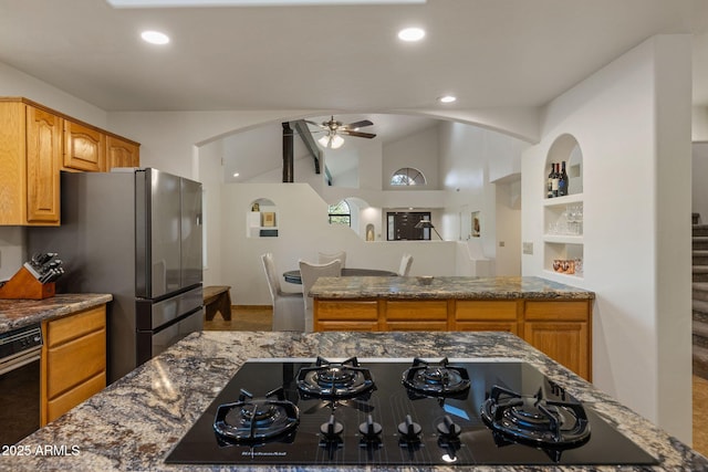 kitchen featuring lofted ceiling, ceiling fan, dark stone countertops, freestanding refrigerator, and black gas cooktop