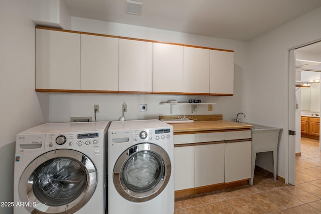 laundry room with visible vents, light tile patterned floors, cabinet space, and washer and dryer