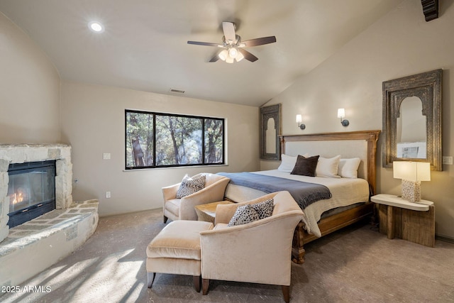 carpeted bedroom featuring visible vents, vaulted ceiling, a ceiling fan, and a stone fireplace