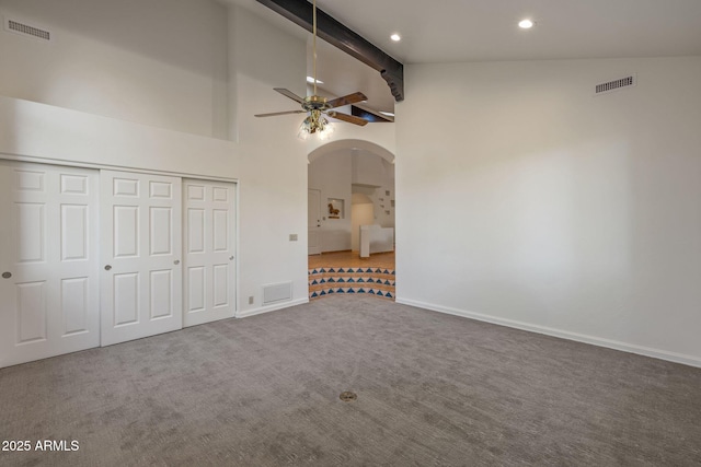 unfurnished bedroom with arched walkways, carpet floors, high vaulted ceiling, and visible vents