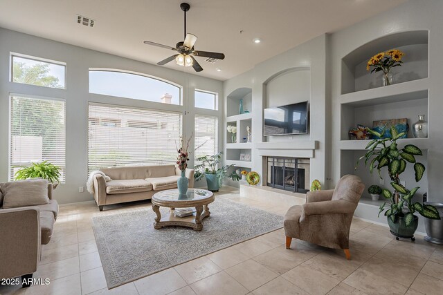 9678 E Voltaire Dr, Scottsdale, AZ 85260 - tiled living room with built in shelves, ceiling fan, a tiled fireplace, baseboards, and recessed lighting