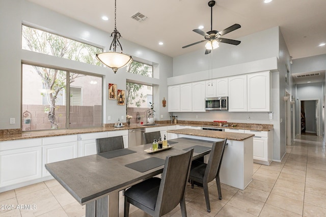 9678 E Voltaire Dr, Scottsdale, AZ 85260 - kitchen featuring appliances with stainless steel finishes, light stone counters, a ceiling fan, white cabinets, and hanging light fixtures