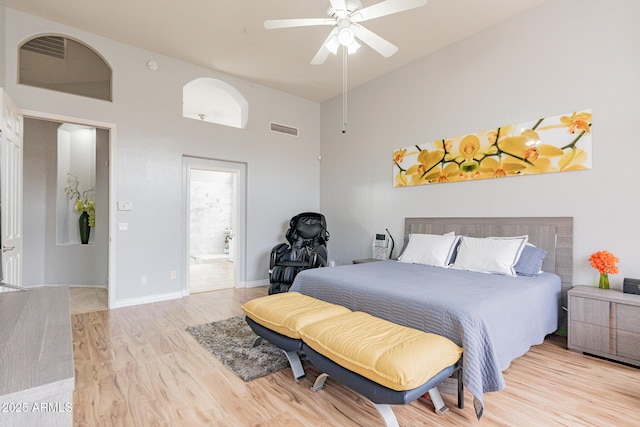9678 E Voltaire Dr, Scottsdale, AZ 85260 - bedroom featuring a towering ceiling, light wood-style floors, baseboards, ensuite bath, and a ceiling fan