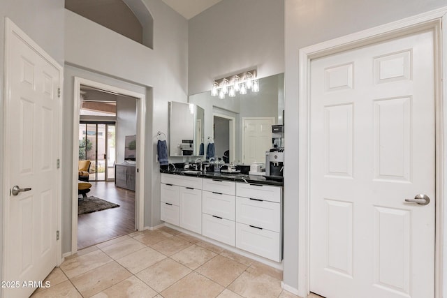 9678 E Voltaire Dr, Scottsdale, AZ 85260 - bathroom featuring double vanity, ensuite bath, tile patterned flooring, a towering ceiling, and baseboards