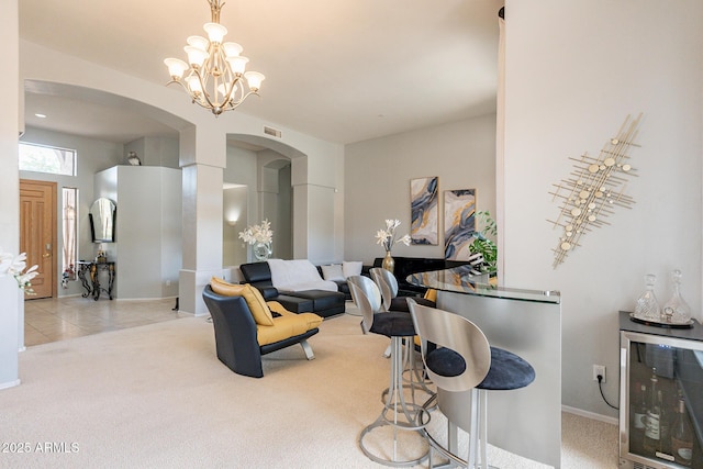 9678 E Voltaire Dr, Scottsdale, AZ 85260 - living area with arched walkways, beverage cooler, carpet flooring, baseboards, and a chandelier