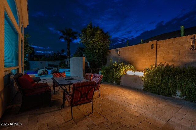 9678 E Voltaire Dr, Scottsdale, AZ 85260 - patio at twilight featuring a patio area, a fenced backyard, outdoor dining space, and a swimming pool