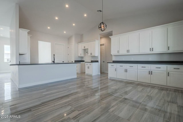 kitchen featuring lofted ceiling, sink, a kitchen island with sink, white cabinets, and decorative light fixtures