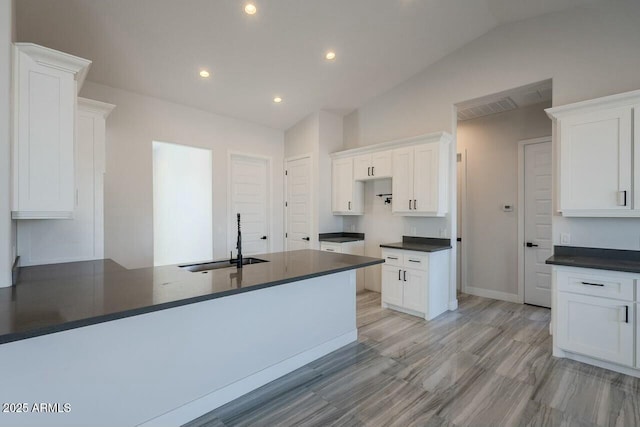 kitchen featuring lofted ceiling, sink, light hardwood / wood-style flooring, and white cabinets