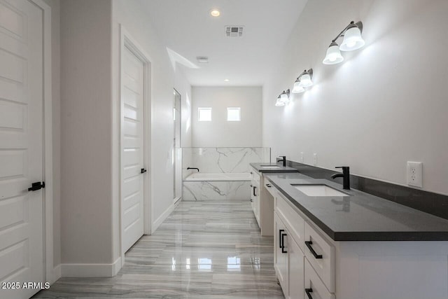 bathroom featuring vanity and tiled bath