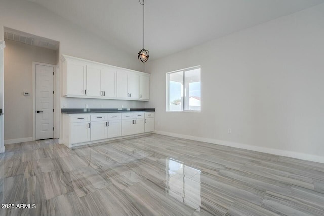 kitchen featuring pendant lighting, vaulted ceiling, and white cabinets