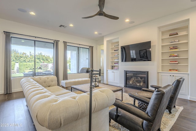 living room featuring wood-type flooring, built in features, and ceiling fan